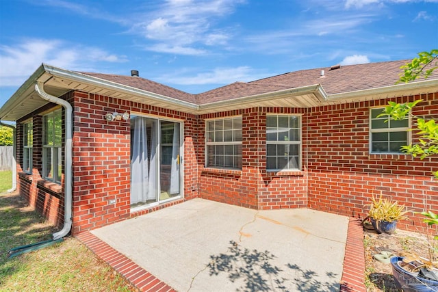 back of house featuring brick siding and a patio