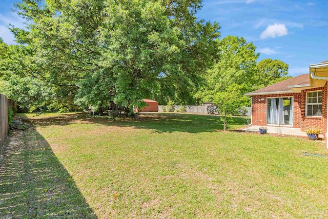 view of yard with a fenced backyard, an outbuilding, and a storage unit