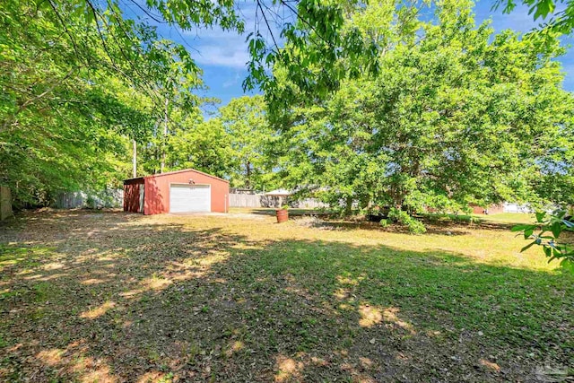 view of yard with an outdoor structure, a garage, and fence