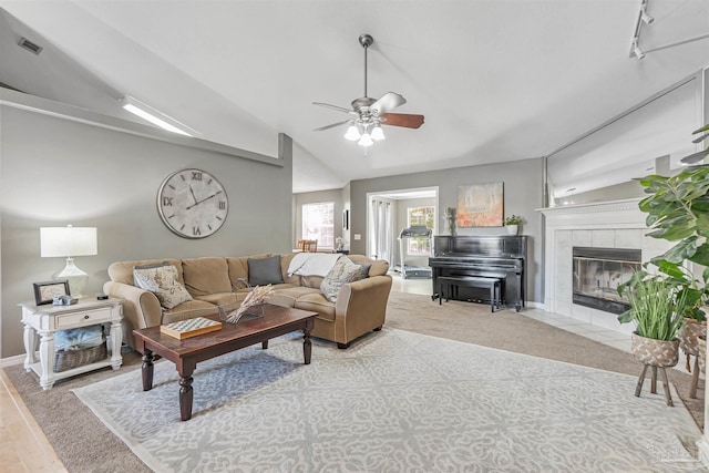 carpeted living area featuring baseboards, visible vents, lofted ceiling, a ceiling fan, and a fireplace