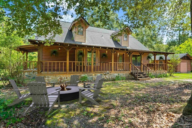 rear view of property featuring an outdoor fire pit and roof with shingles