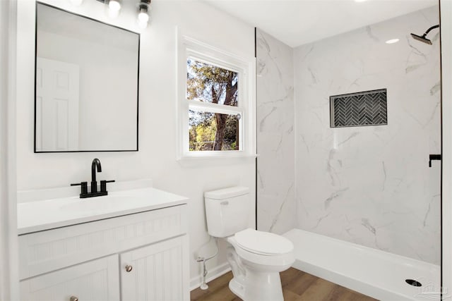 bathroom with vanity, toilet, wood-type flooring, and a tile shower