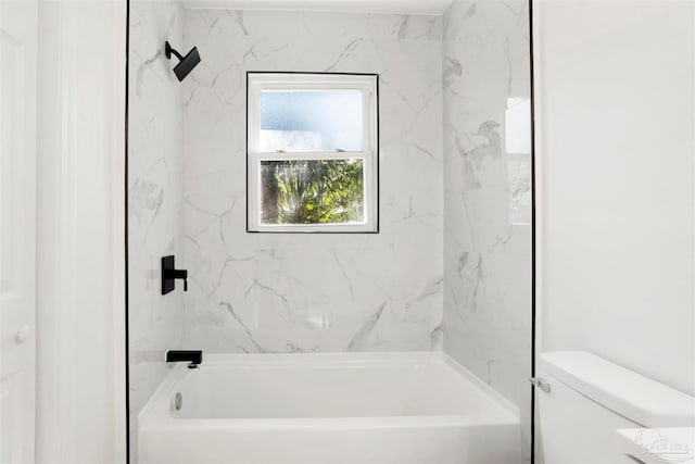 bathroom featuring tiled shower / bath combo and toilet