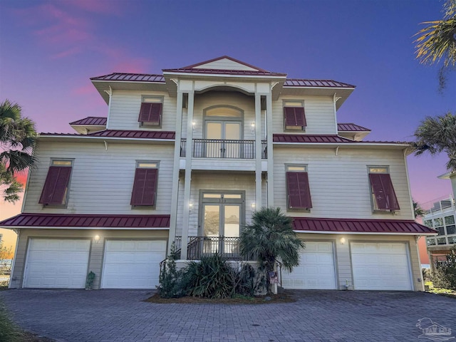 view of front of house featuring a balcony, metal roof, an attached garage, a standing seam roof, and french doors