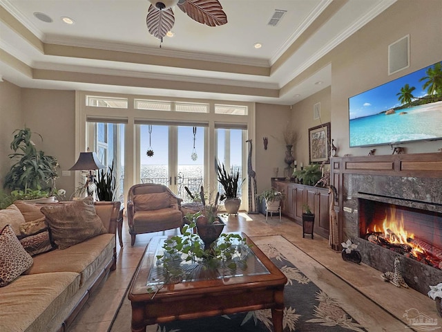 living room with a fireplace, visible vents, ornamental molding, french doors, and a tray ceiling