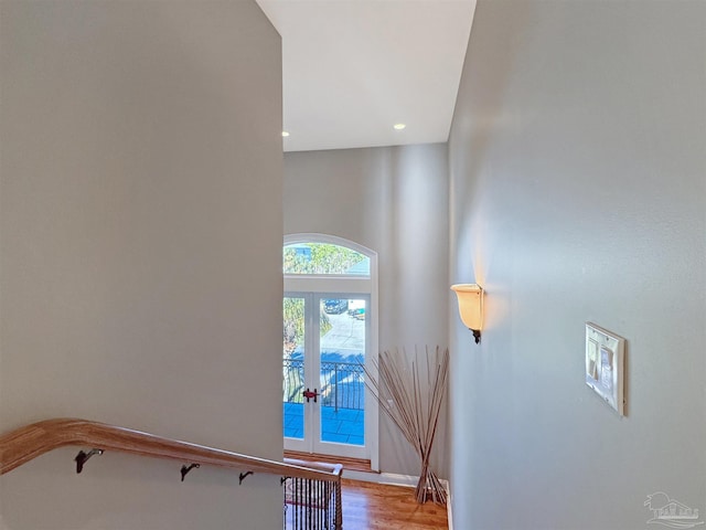 stairs with french doors, wood finished floors, and recessed lighting