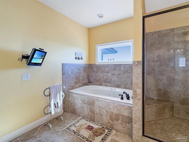 bathroom with tile patterned floors, a stall shower, a garden tub, and baseboards