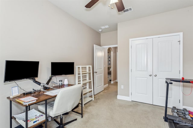 home office featuring a ceiling fan, baseboards, visible vents, arched walkways, and light colored carpet