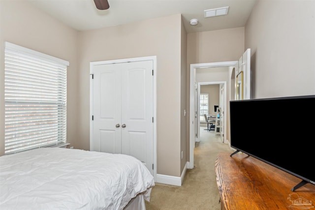 bedroom with visible vents, ceiling fan, baseboards, light carpet, and a closet