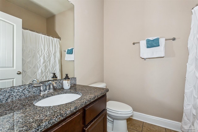 bathroom with baseboards, toilet, vanity, and tile patterned flooring