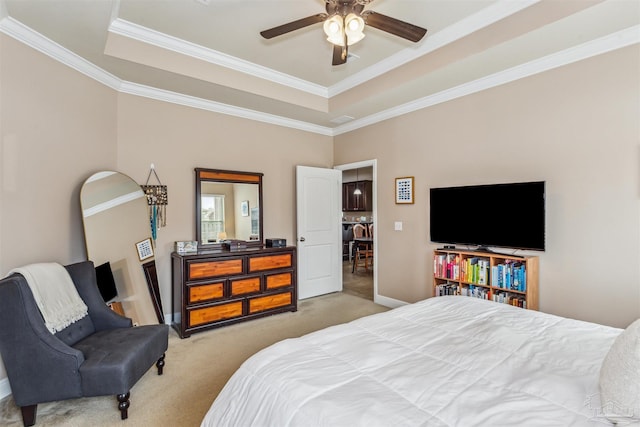 carpeted bedroom with a ceiling fan, a tray ceiling, crown molding, and baseboards