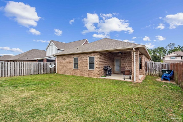 rear view of property featuring brick siding, ceiling fan, a fenced backyard, a yard, and a patio area