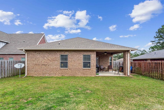 back of house featuring a fenced backyard, a shingled roof, a lawn, a patio area, and brick siding