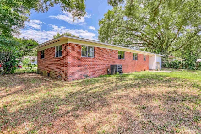 back of property featuring central air condition unit and a yard