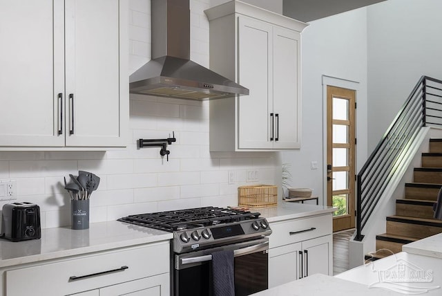 5611 Trout Ln, Pensacola, FL 32507 - kitchen featuring wall chimney range hood, stainless steel gas range, backsplash, and white cabinetry