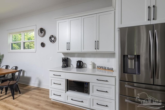 5611 Trout Ln, Pensacola, FL 32507 - kitchen featuring stainless steel fridge with ice dispenser, light countertops, light wood-style floors, baseboards, and black microwave