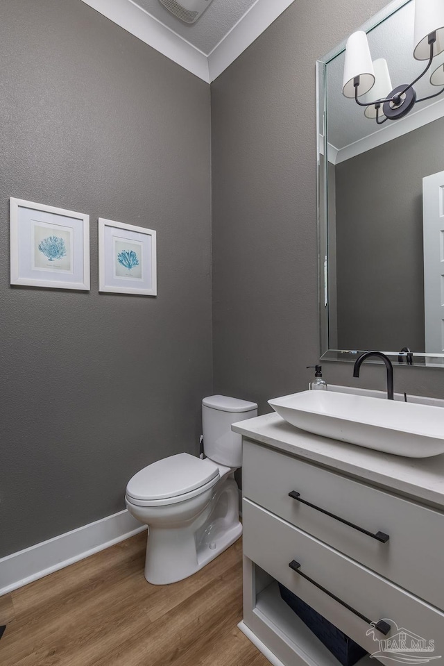 5611 Trout Ln, Pensacola, FL 32507 - half bathroom featuring wood finished floors, vanity, toilet, ornamental molding, and baseboards
