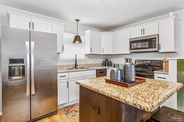 kitchen featuring light wood finished floors, appliances with stainless steel finishes, a sink, and white cabinets