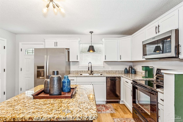 kitchen featuring light wood-style flooring, a kitchen island, a sink, white cabinets, and black appliances