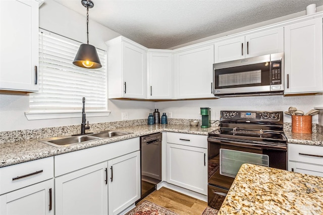 kitchen featuring pendant lighting, white cabinets, a sink, a textured ceiling, and black appliances