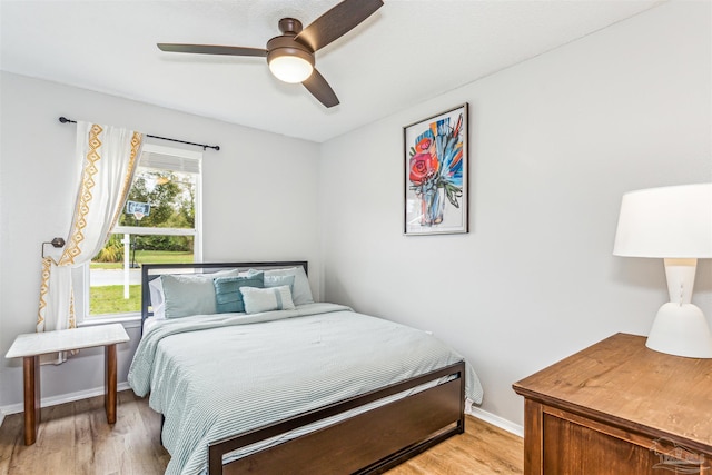 bedroom featuring a ceiling fan, light wood-style flooring, and baseboards