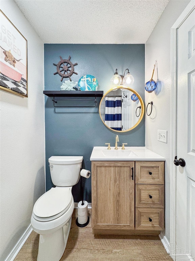 full bathroom featuring a shower with shower curtain, toilet, vanity, a textured ceiling, and baseboards