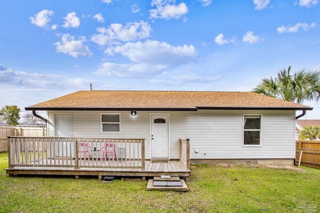 rear view of property featuring fence, a lawn, and a wooden deck