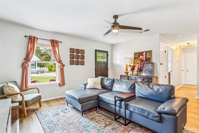 living area with a ceiling fan, visible vents, light wood-style flooring, and baseboards