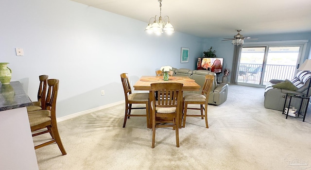 dining space with ceiling fan with notable chandelier and light colored carpet