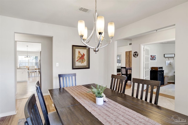 dining area with sink, light hardwood / wood-style flooring, and a notable chandelier