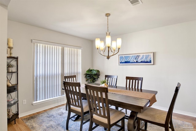 dining space featuring wood-type flooring and a notable chandelier