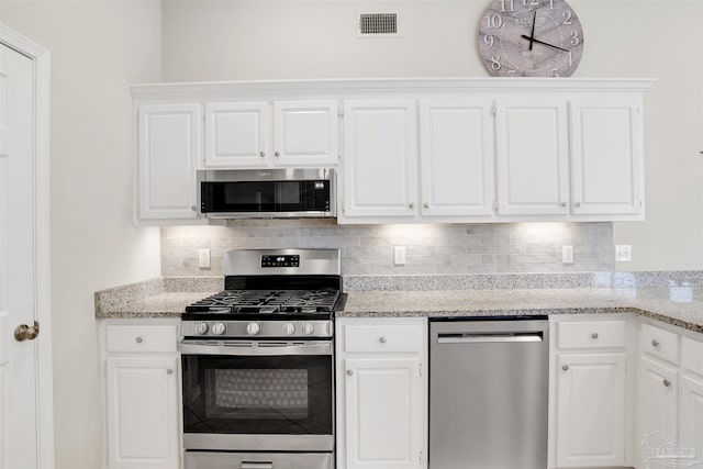 kitchen with backsplash, appliances with stainless steel finishes, light stone counters, and white cabinetry