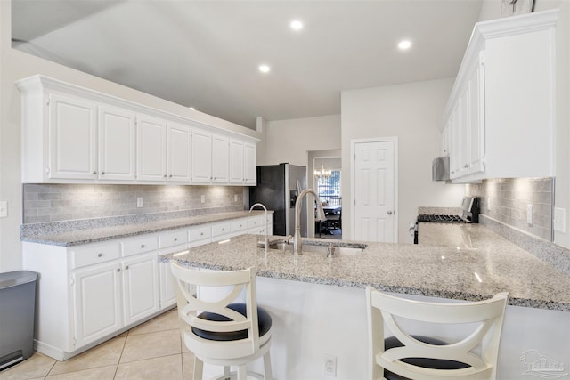 kitchen with a kitchen breakfast bar, kitchen peninsula, white cabinets, and sink