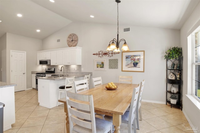 dining area with a wealth of natural light, vaulted ceiling, sink, and a chandelier