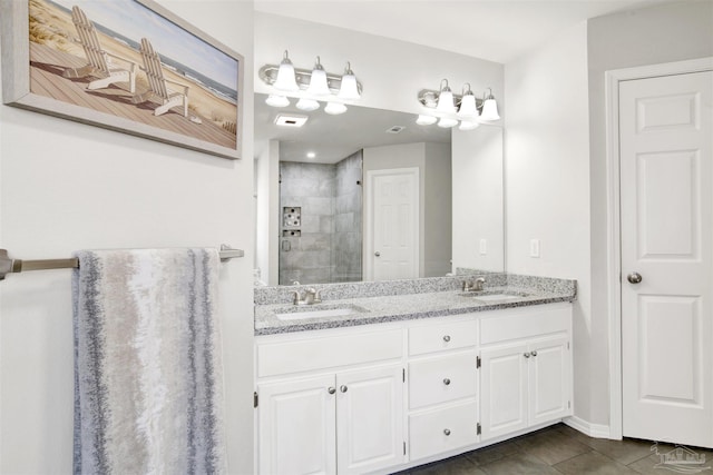 bathroom featuring tiled shower, vanity, and tile patterned flooring