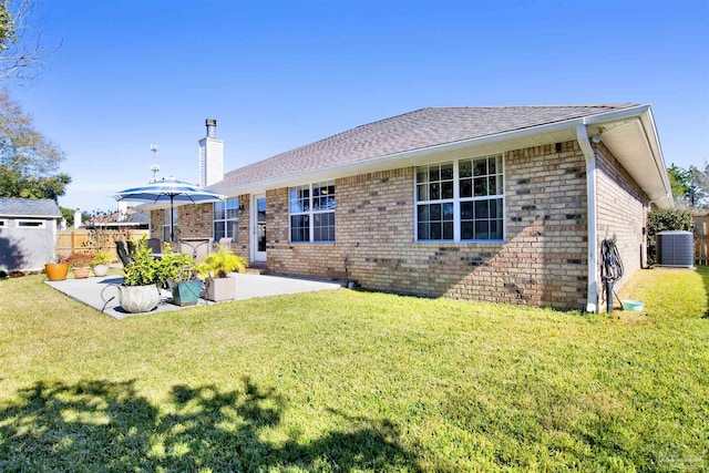 rear view of house with a patio area, a yard, and central AC