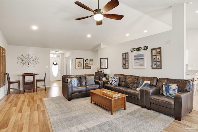 living room with light wood-type flooring, ceiling fan, and vaulted ceiling