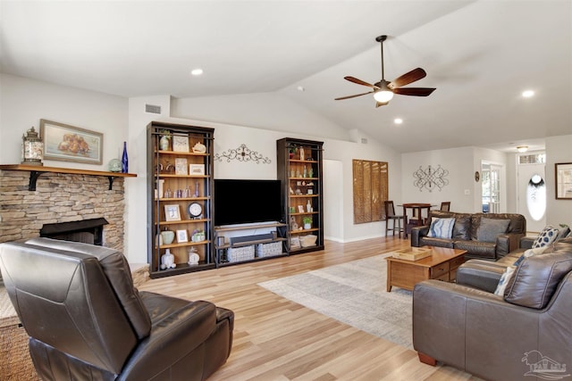 living room with ceiling fan, light wood-type flooring, a fireplace, and vaulted ceiling