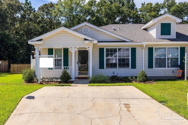 view of front of property featuring covered porch, roof with shingles, a front yard, and fence