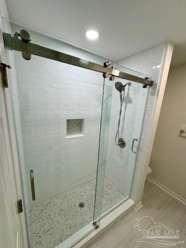 bathroom featuring toilet, baseboards, and a stall shower