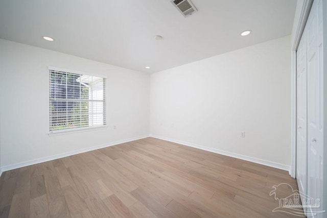 empty room featuring visible vents, baseboards, and wood finished floors