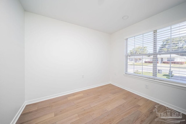 spare room featuring light wood finished floors and baseboards