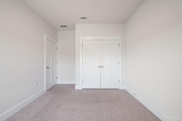 unfurnished bedroom with light colored carpet and a closet