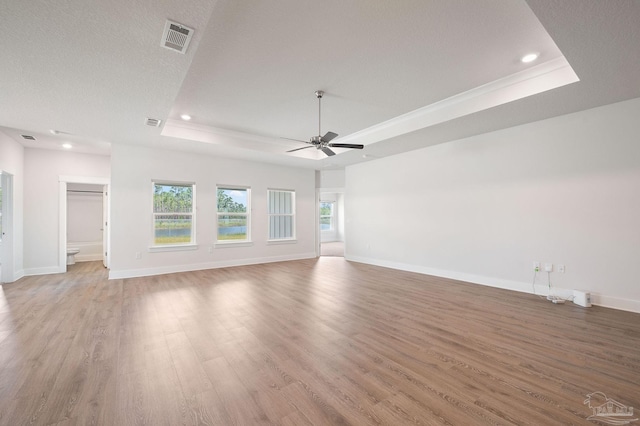 unfurnished living room featuring ceiling fan, a raised ceiling, hardwood / wood-style floors, and a textured ceiling