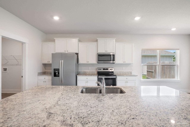 kitchen featuring sink, a textured ceiling, appliances with stainless steel finishes, light stone countertops, and white cabinets