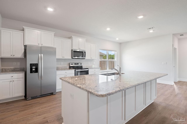 kitchen with a kitchen island with sink, sink, white cabinetry, and appliances with stainless steel finishes