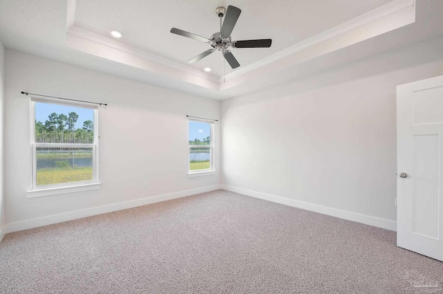 carpeted spare room featuring a raised ceiling, ornamental molding, and ceiling fan