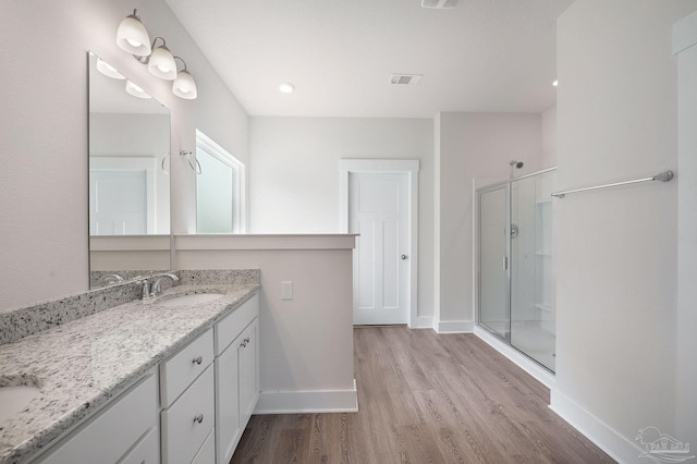 bathroom with hardwood / wood-style flooring, vanity, and an enclosed shower