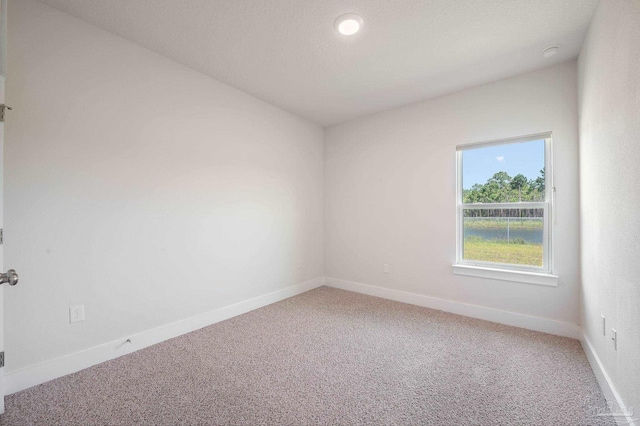 carpeted empty room with lofted ceiling