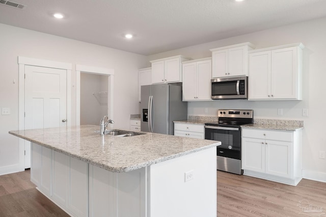 kitchen featuring stainless steel appliances, a center island with sink, and white cabinets